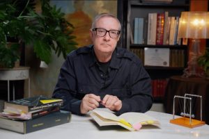 Michael Glock, PhD, co-founder of Joymind, seated at a table with open books in his library