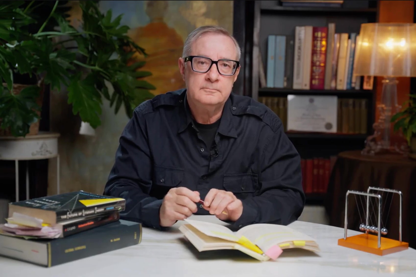 Michael Glock, PhD, co-founder of Joymind, seated at a table with open books in his library